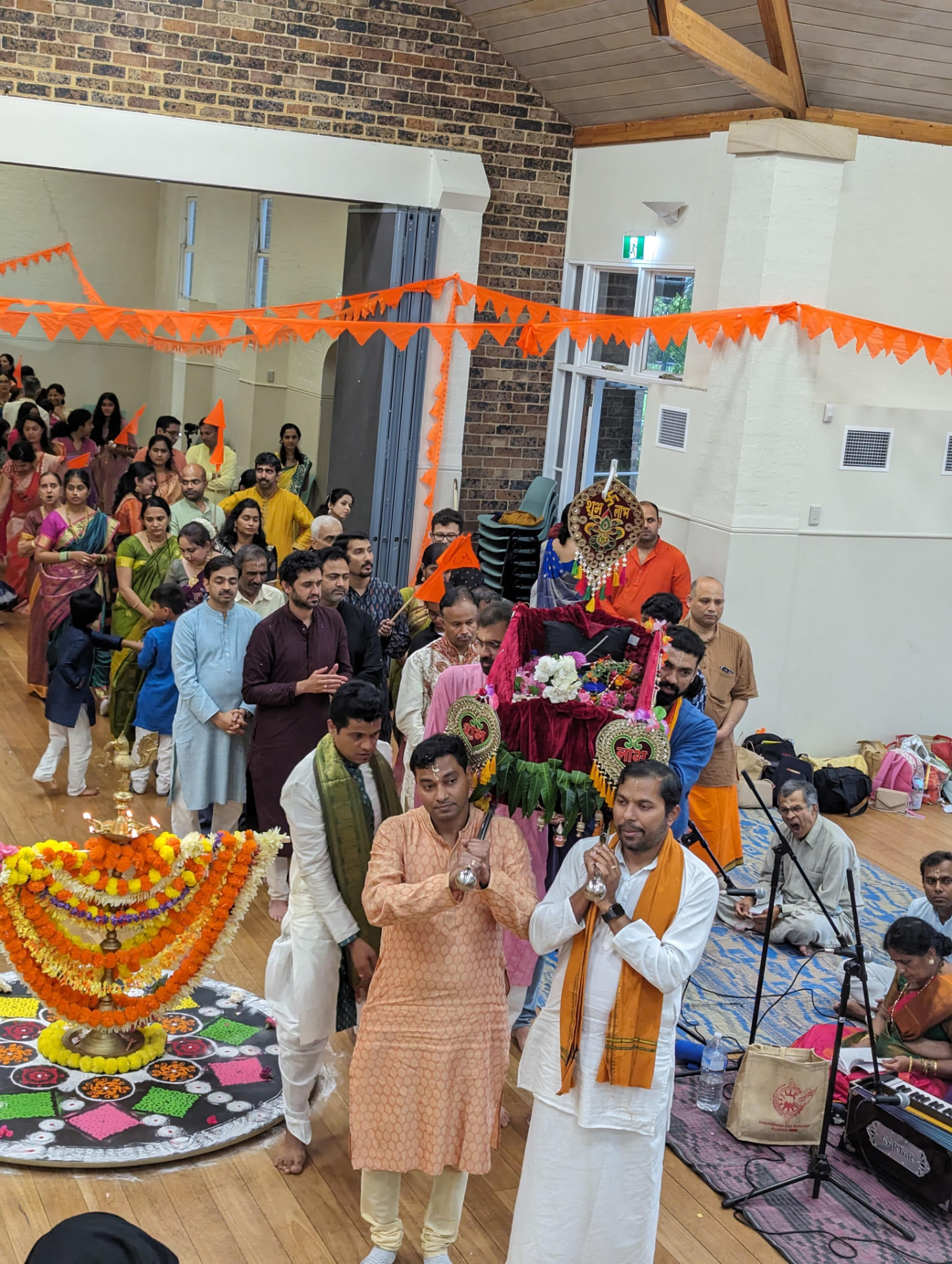 The palki procession carried through the hall amid saffron bunting
