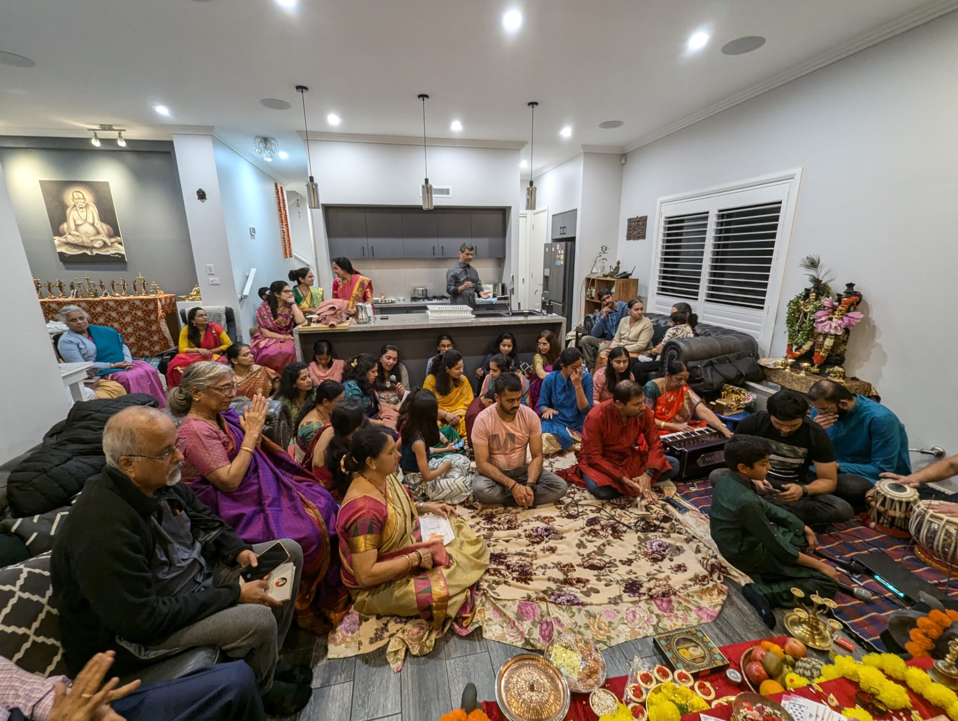 Families seated together for the Varamahalakshmi bhajans — harmonium, tabla and voices as one